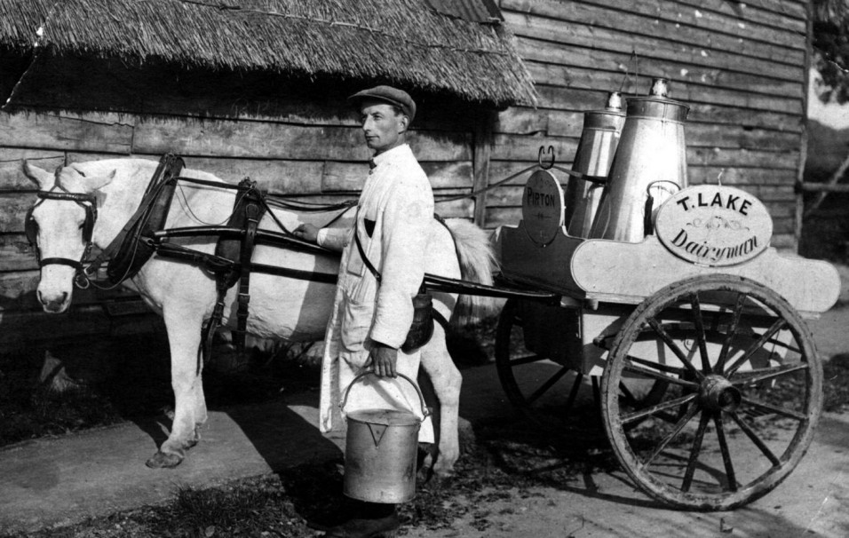 1926 Tom Lake, Pirton’s first milkman, with his churns, pails and measuring jugs. He delivered milk twice a day as there were no fridges to keep milk cool. Milk was “straight from the cow” and was not pasteurised as is now required by health legislation