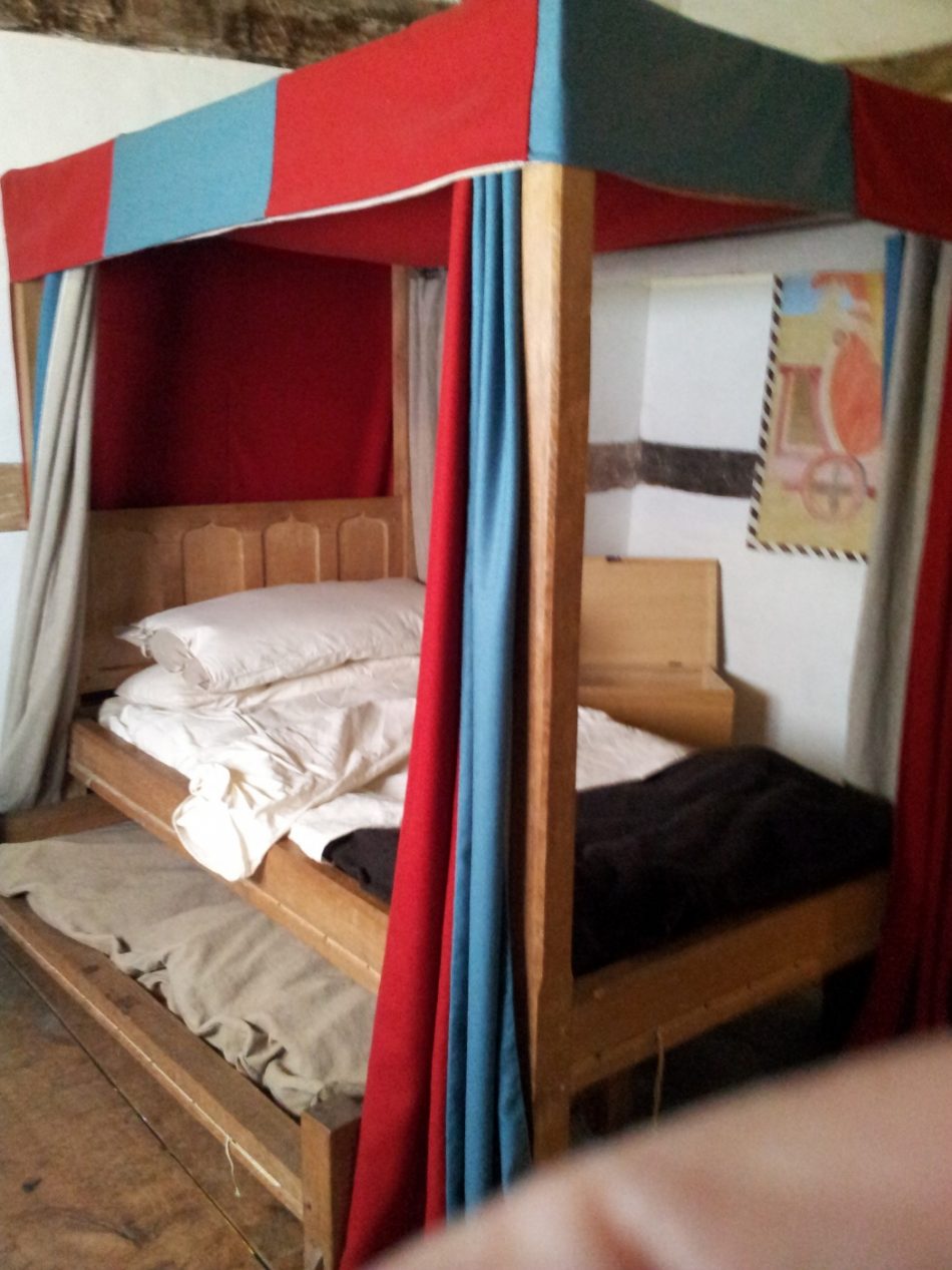 A valence and canopy bed with a truckle bed in a poor household.The small truckle bed was usually for children or servants.

