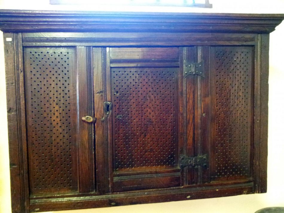 A cupboard with ventilation holes for dry goods and kitchen utensils.
