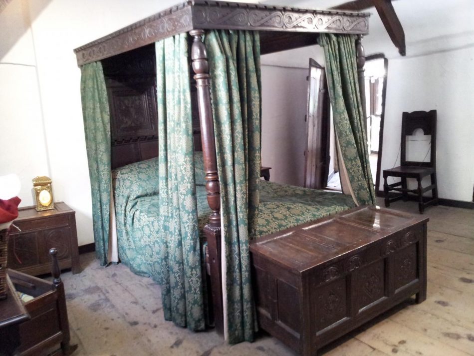 A posted bed with 4 posts with a wooden canopy or ceiling.The coffer at the foot of the bed was for the linen.